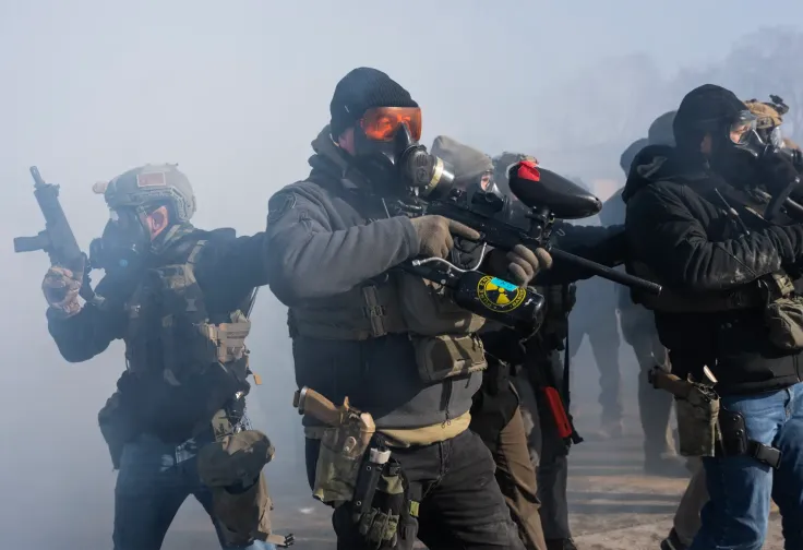 ICE (Immigration and Customs Enforcement) officers and federal agents stand in a chemical haze fully masked with weapons drawn clash with a growing crowd of protesters on Nicollet Avenue in south Minneapolis after Alex Pretti was fatally shot.