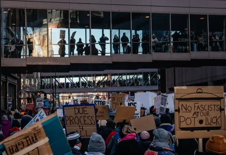 People marched through downtown Minneapolis in late January to protest the Trump administration’s immigration crackdown in Minnesota, holding cardboard signs including Due Process 4 All and No Fascists at our Potluck.